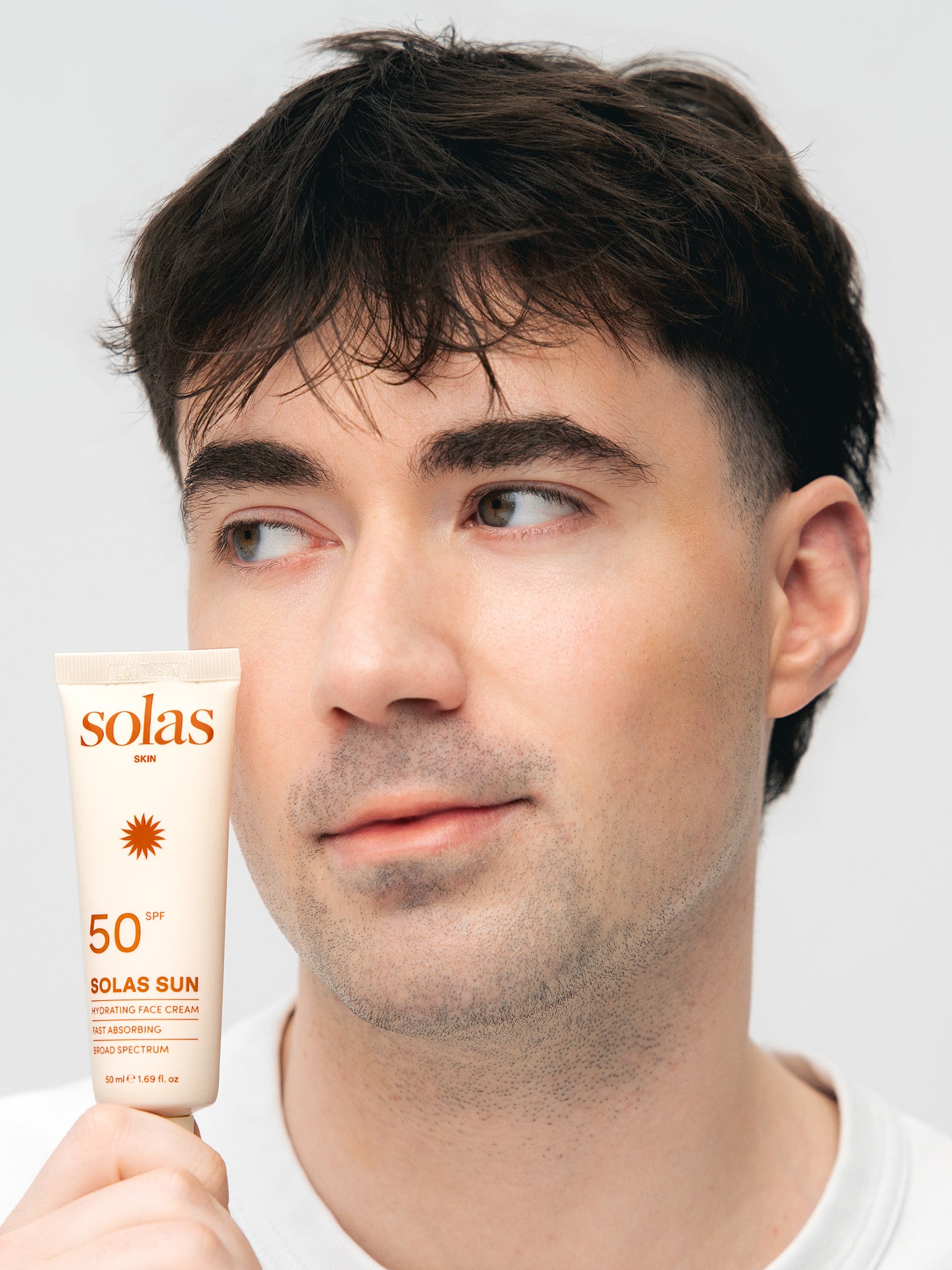 Man holding a Solas Sun cream tube against a plain background