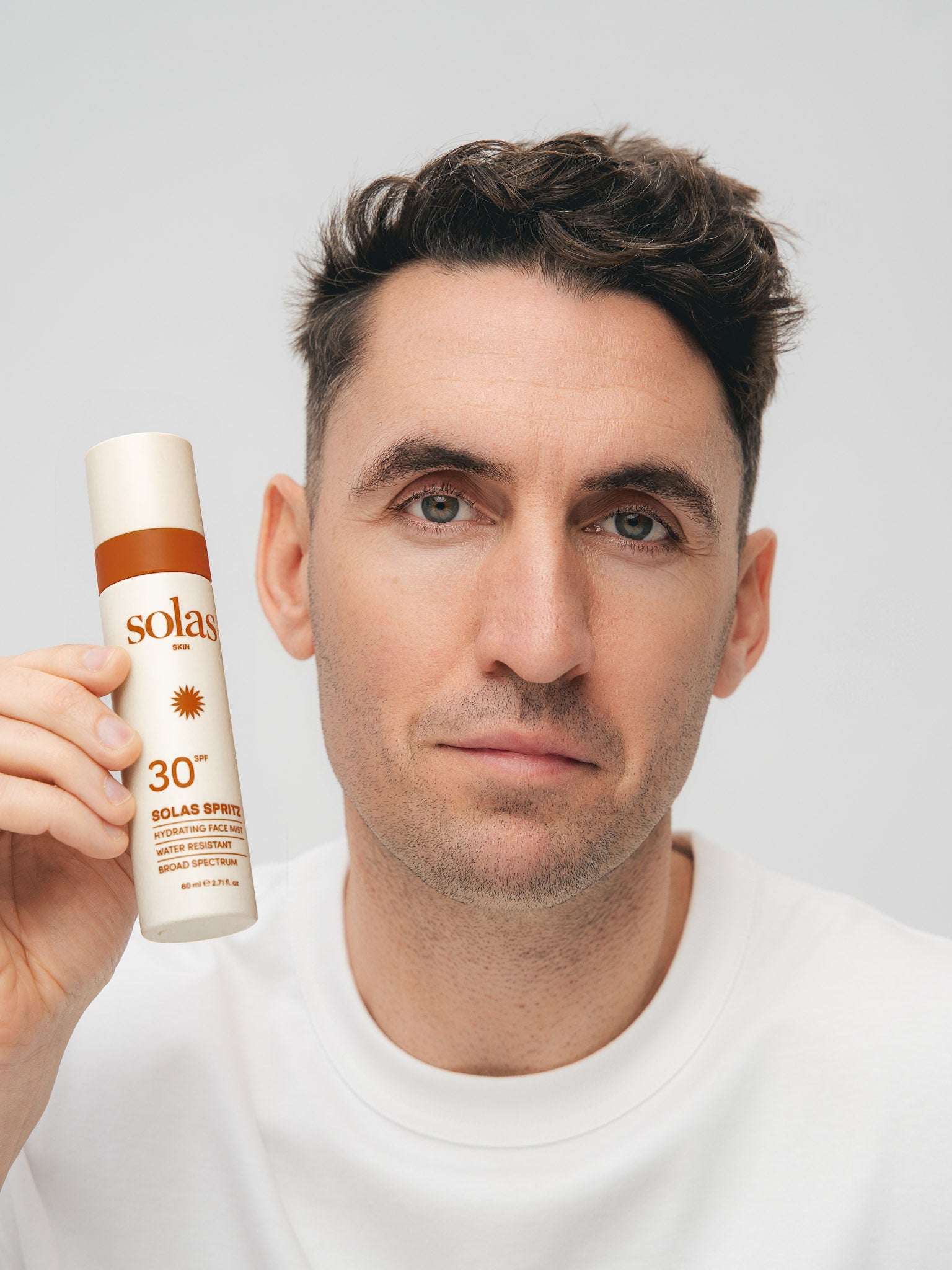 Man holding a Solas Spritz bottle against a plain background