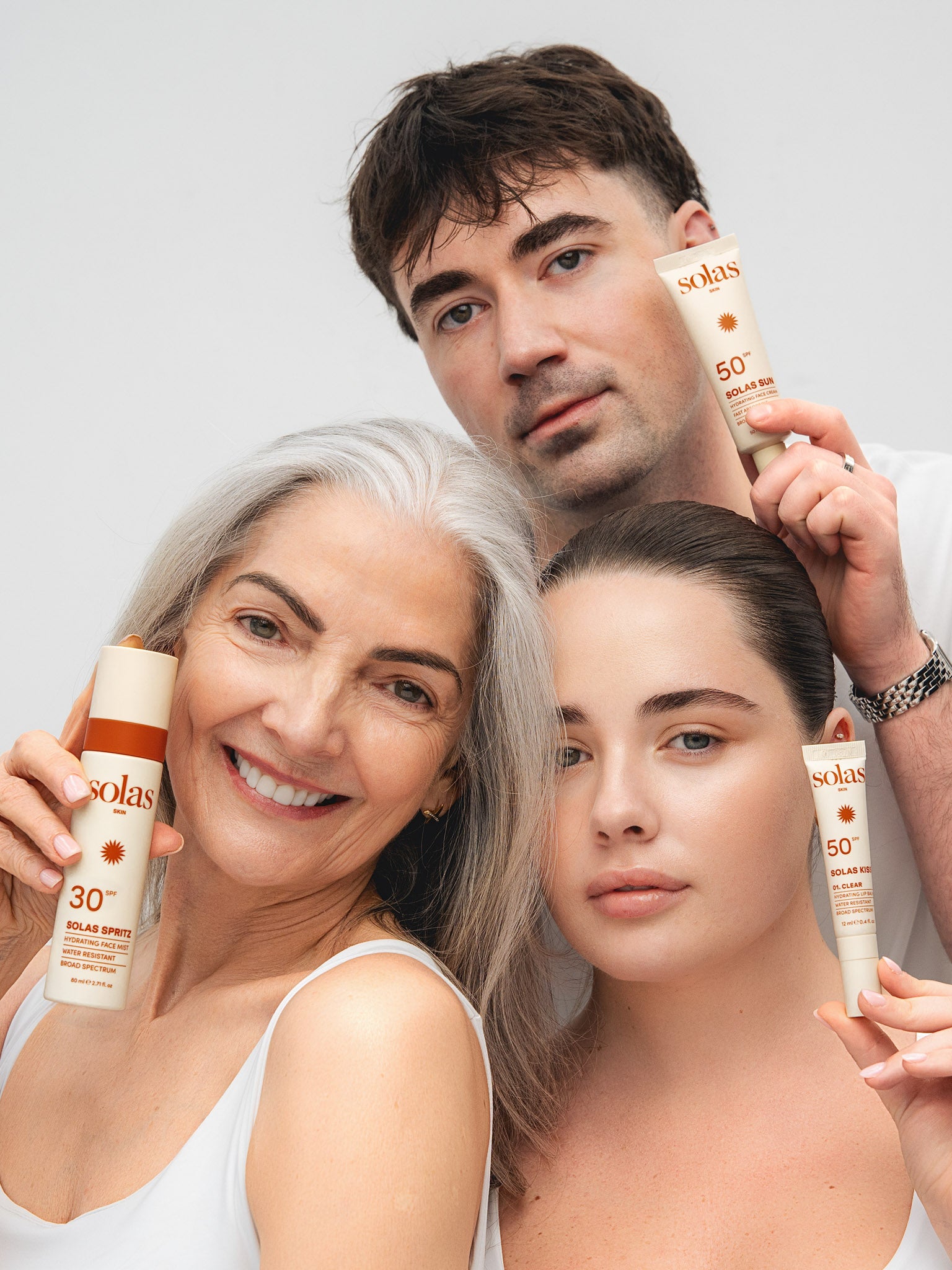 Three people holding the Solas Skin Set against a light background